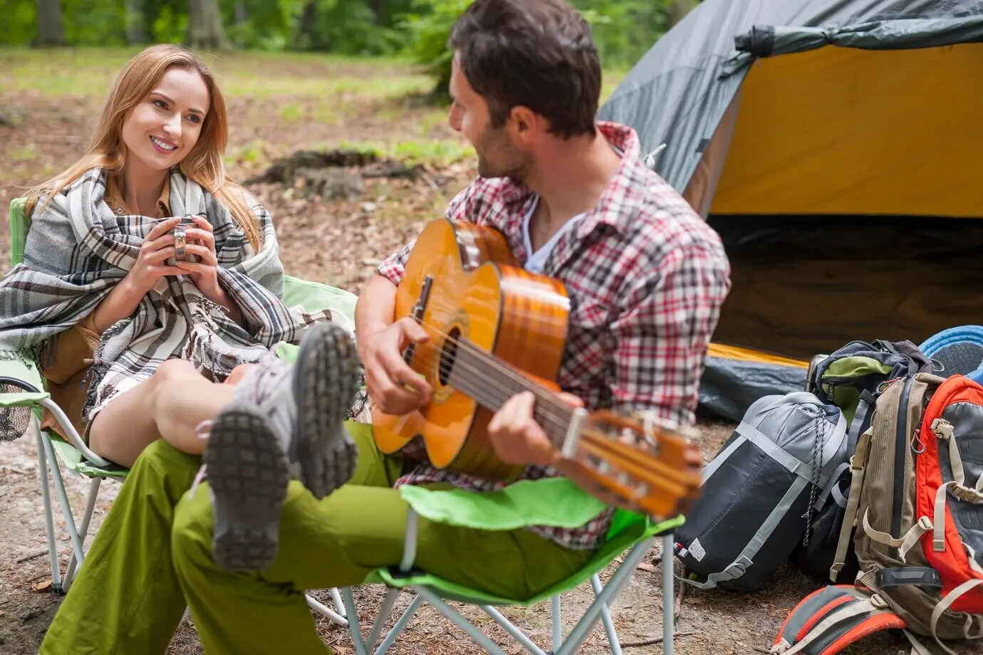 Romantisches Paar beim Camping. Der Mann spielt Gitarre.
